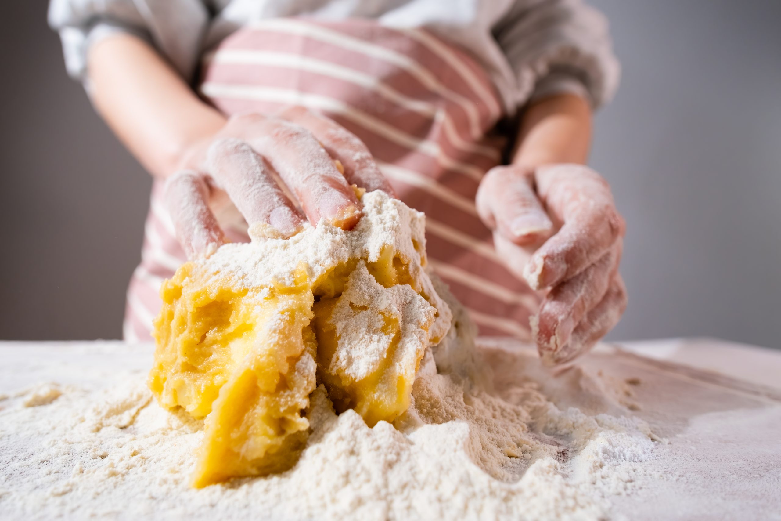 Wide angle of woman hand kneading of dough for pizza, cookies, bins or gingerbreads on the wooden desk. Home made pastry.